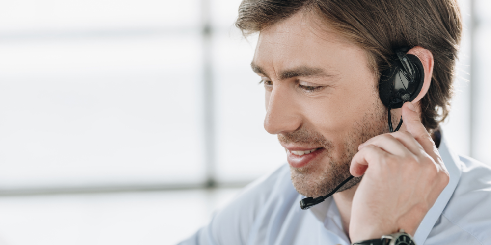 Un conseiller en assurance souriant dans des écouteurs avec microphone au travail